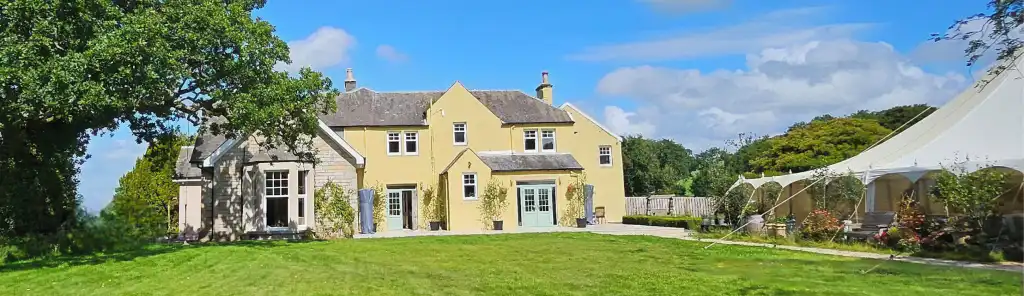 Panoramic view of the Yoga, Meditation and Healing retreat grounds at Ladyburn House Scotland, featuring the main country house and outdoor wellness marquee.